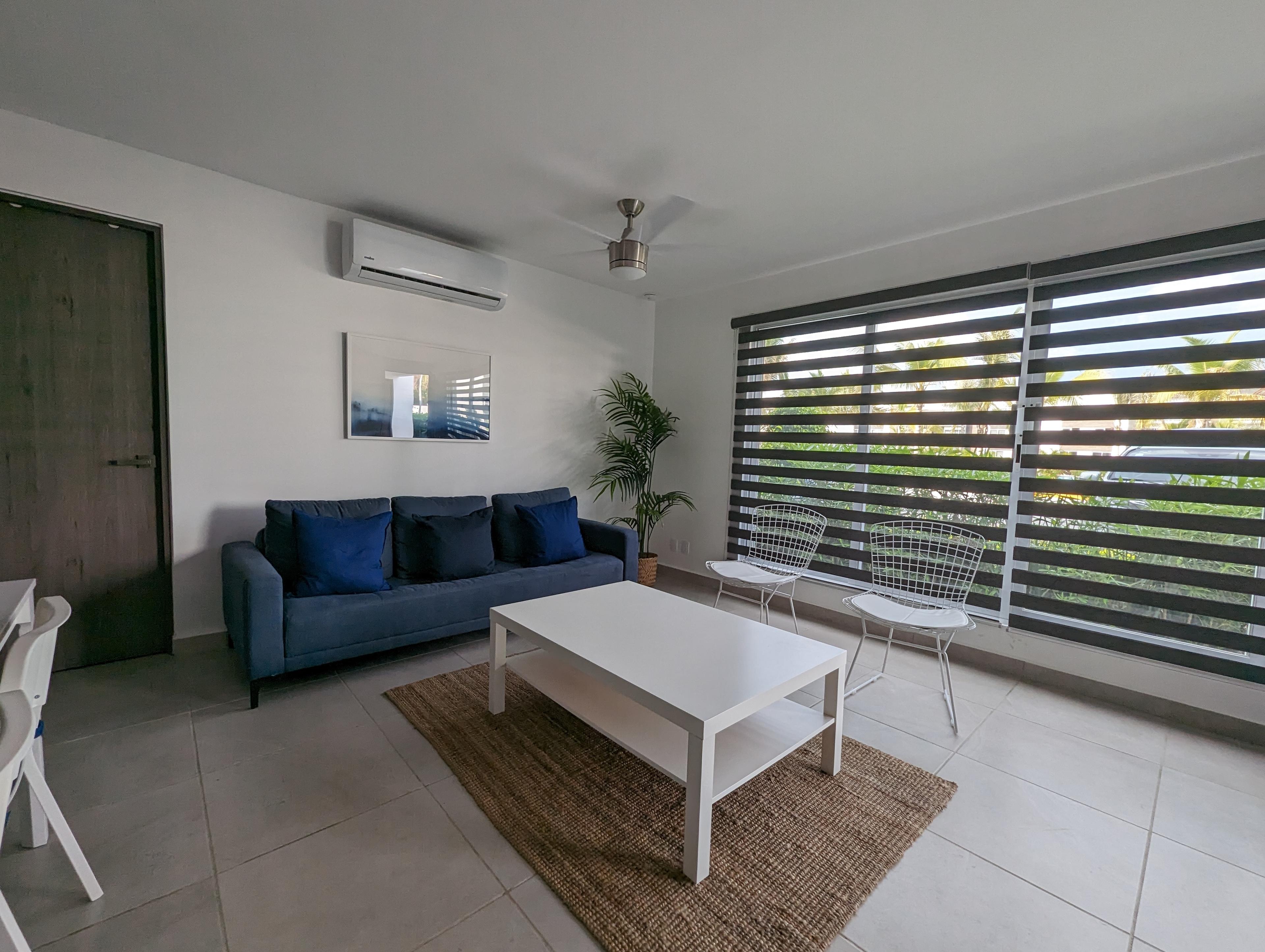 Sala con sofá azul marino y vista al jardín